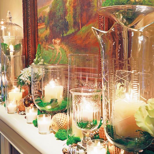 The contrasting textures of natural moss and clear glass create an inviting mantlescape, while candlelight adds elegance with its subtle glow.