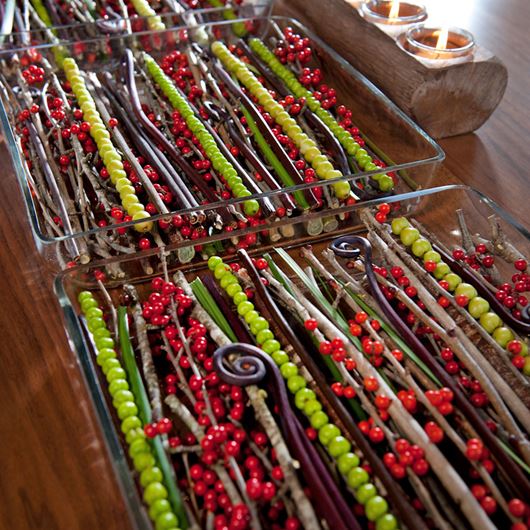 Winter reds and greens shine in this tablescape display featuring Hypericum berries, Ilex, waxy lily grass and fern fronds.