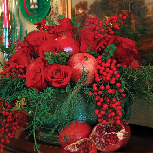 Fresh pomegranates, Nandina berries and deep red roses creates a punch of red color in an evergreen arrangement.