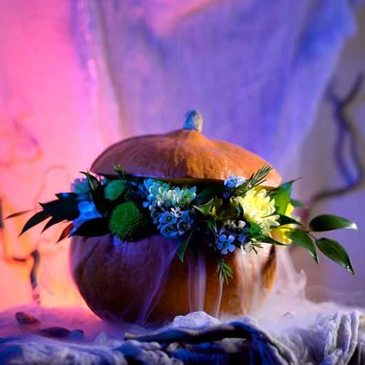 Elevate your Halloween floral decor using a spooky container, like a hollowed-out pumpkin.