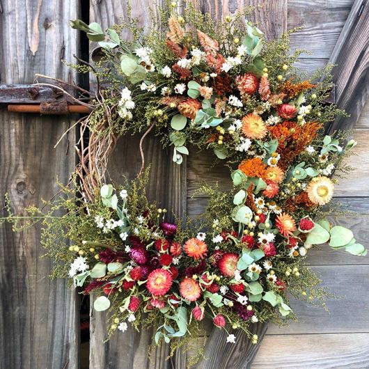 A rustic, winter wreath featuring an array of dried flowers and foliage.