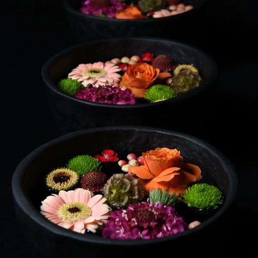 Floating bowls of miniature Gerberas, Chrysanthemums, roses, Scabiosa, and Scabiosa pods.. 