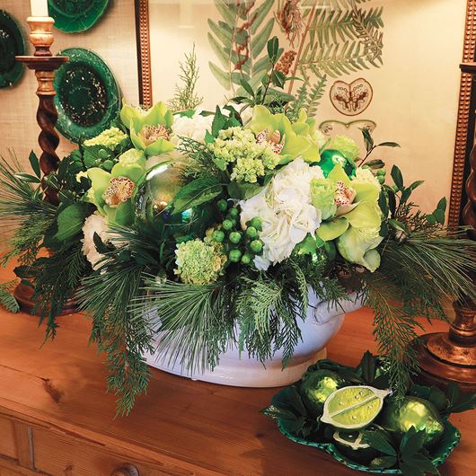 Glass ornaments in zesty green create a contrast of textures when paired with green Cymbidium orchids, Hydrangea and assorted evergreens.