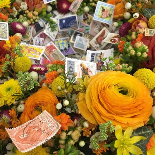 An array of Ranunculus, mums, Craspedia and Kalanchoe set the stage for this whimsical stamp display.