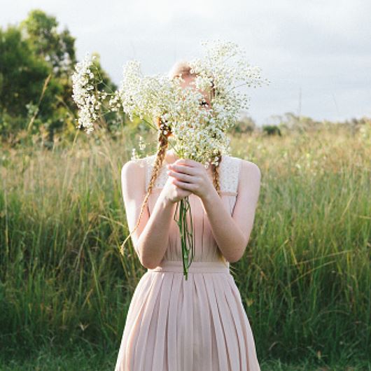 Girl in meadow holding Gypsophila ​stems.