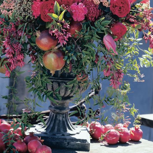 Romantic urn display featuring pomegranates and garden roses.