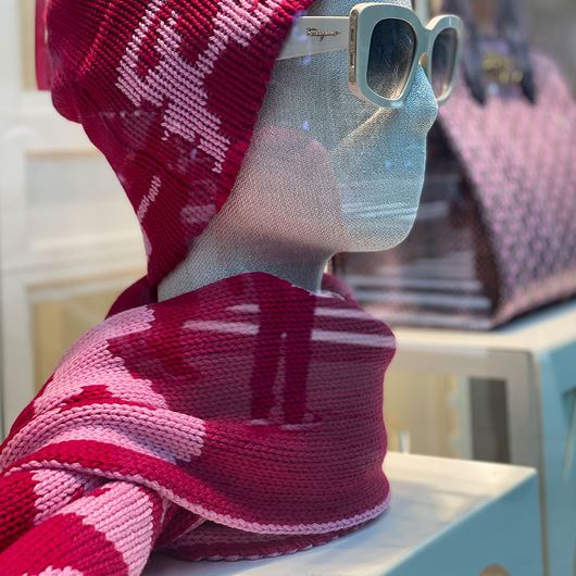 Window display at Bergdorf Goodman showcasing winter accessories featuring light pink and Christmas red.