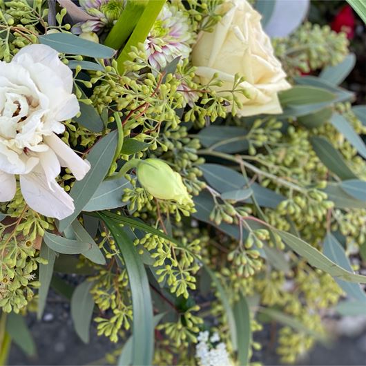 Arrangement feating seeded Eucalyptus, Lisianthus, roses, Hypericum, Veronica and callas.